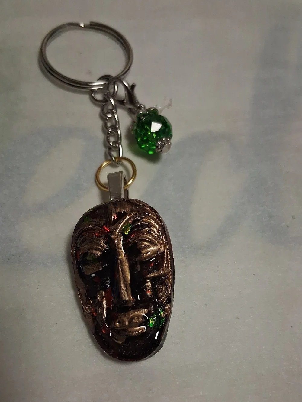 Artisan Bronze Mask Keychain with Green Crystal Accent